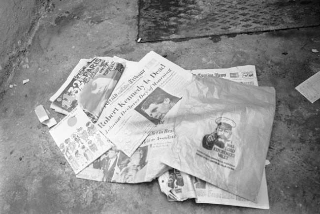 Newspapers, a paper bag and an air travel guide are lying near a dust bin outside the Pax Hotel in Pimlico, London, 1968.