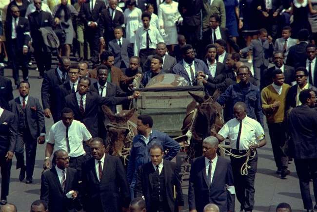 A brace of plow mules draws the farm wagon bearing the casket of Dr. Martin Luther King, Jr., along the funeral procession route in Atlanta, Georgia, 1968.