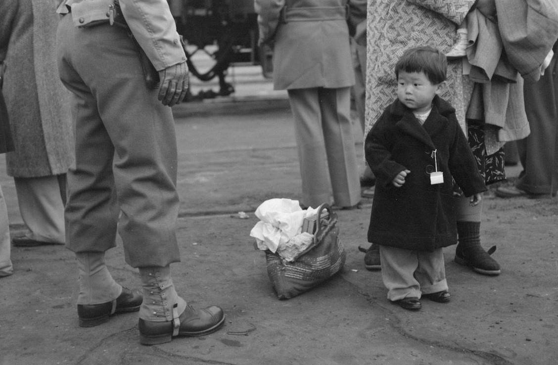 Japanese-American child being evacuated with his parents to Owens Valley, 1942.