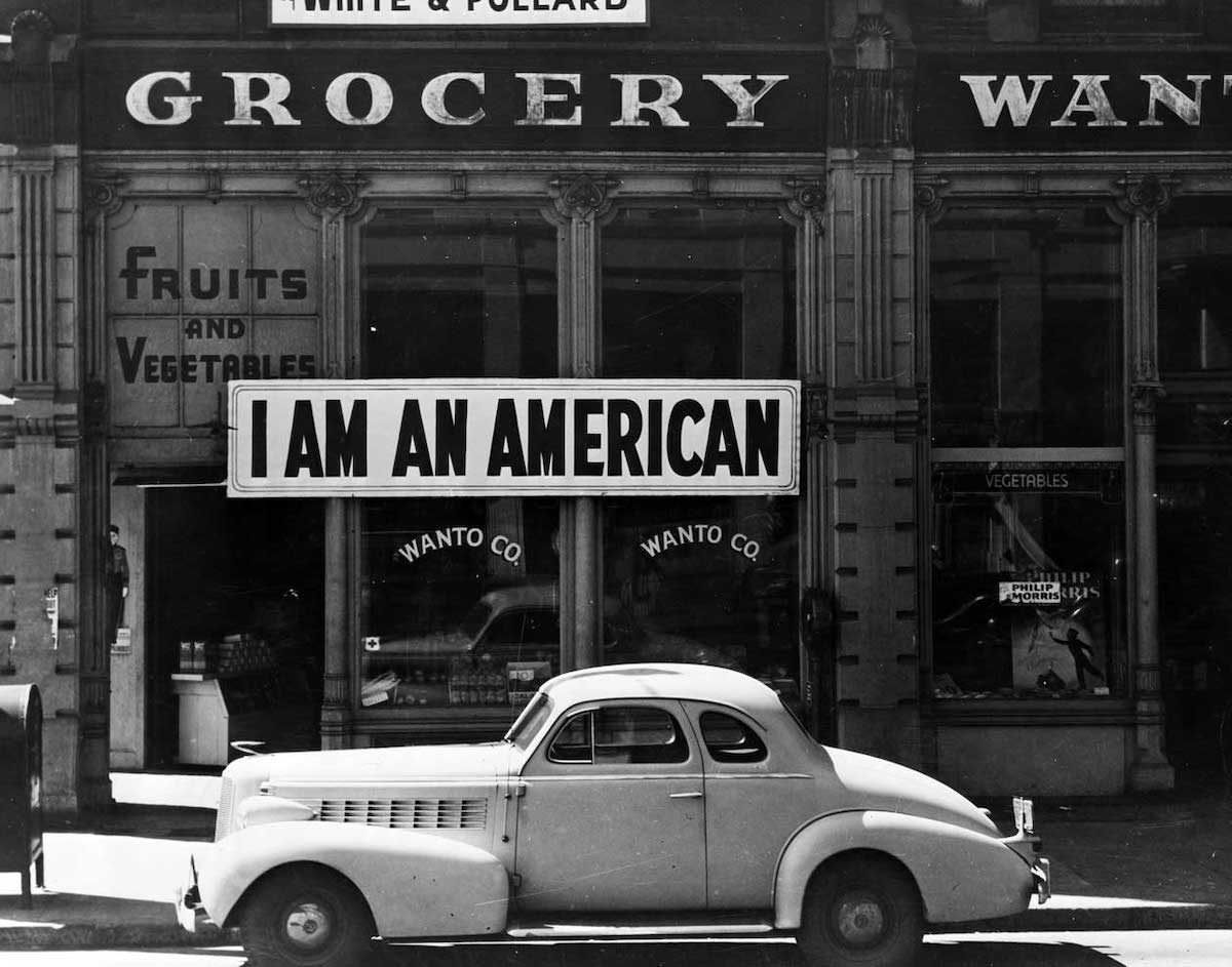 A large sign reading "I am an American" placed in the window of a store, Oakland, California, 1942.