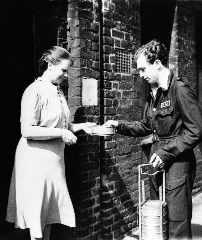 Christopher Ounsted, driver of the mobile canteen, delivering a hot dinner to a woman during his rounds in London on Sept. 17, 1941. The canteen, a gift from the U.S., would be idle normally, as a result of the lull in the blitz, but it is put to use to feed the poor, aged and homeless.