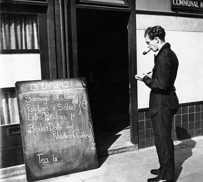 Christopher Ounsted, volunteer driver of the mobile canteen, stops at a communal kitchen to copy the days menu prior to starting out on his day’s rounds in London on Sept. 17, 1941. He presents a list of the food available to the people he visits, permitting them to make a selection.