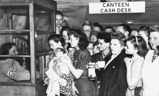 Deep in tubes underneath underground railway lines in London shelters provide safety from buzz bombs, July 25, 1944. They crowd around the canteen cash desk to get receipts for money spent in the canteen on refreshments