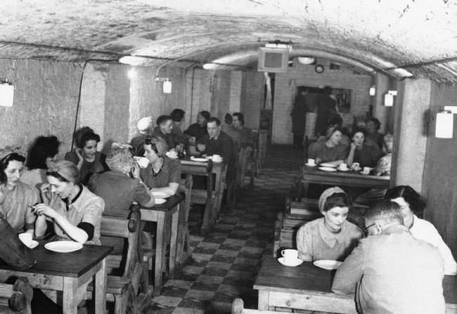 Lunchtime in the underground factoryÂs canteen in England April 11, 1944. Most of the workers are women. The benches are pews from a nearby bombed out church.