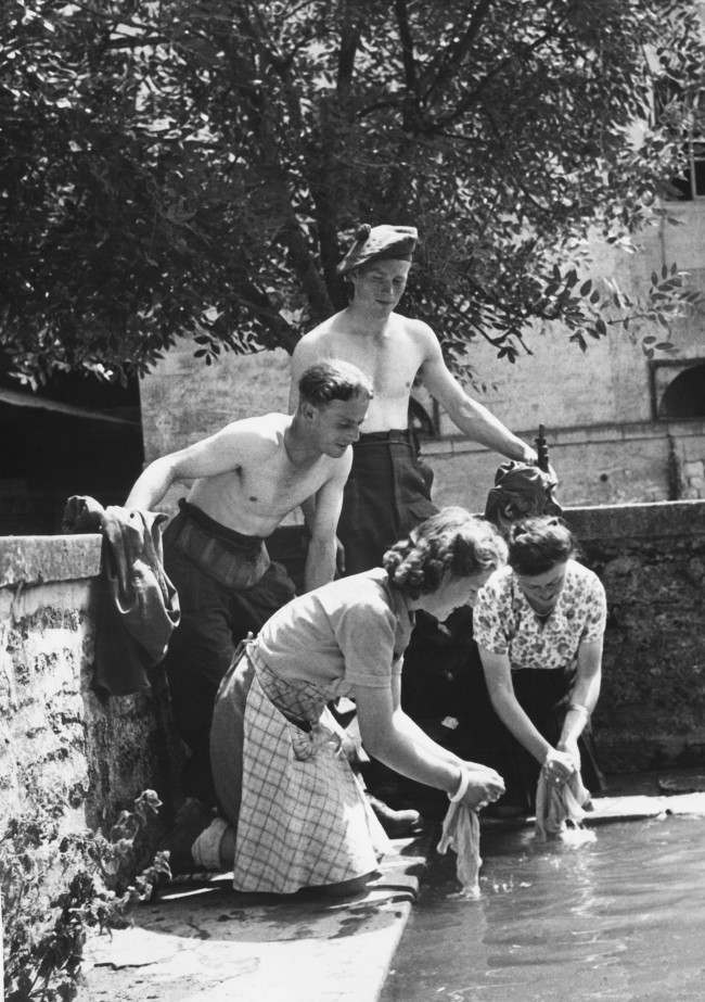 Two British soldiers taking part in the liberation of France from the Germans are rewarded by Frenchwomen, of a Normandy farm, by having their laundry washed for them in France, 1944.