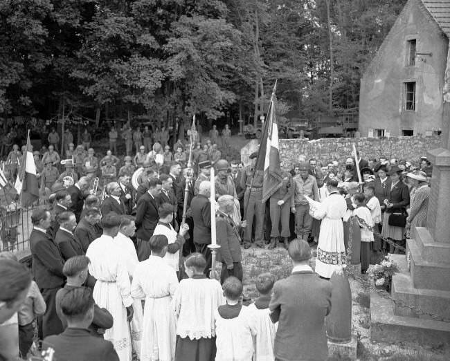 U.S. Army bandsmen attend with French civilians the Bastille Day services held in a church cemetery in the liberated village of Castilly in Normandy, France, 1944.