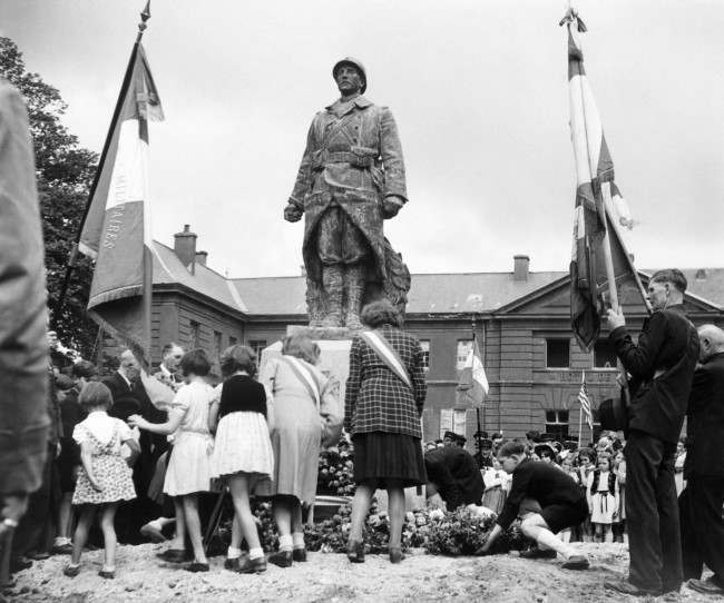 Bastille Day celebrations in the little Normandy town of Isigny, 1944, took the form of services at the town’s War Memorial. French children pass in turn to lay their tributes to war dead at the War Memorial during the services.