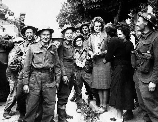 French girls give a hearty welcome to Canadian troops passing through a town in the Normandy coast area of France, 1944.