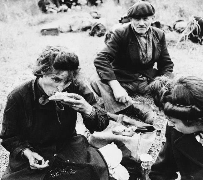 Many of these French refugees had not eaten for three or more days. In a field behind the allied lines they rest and receive food from our troops, 1944.