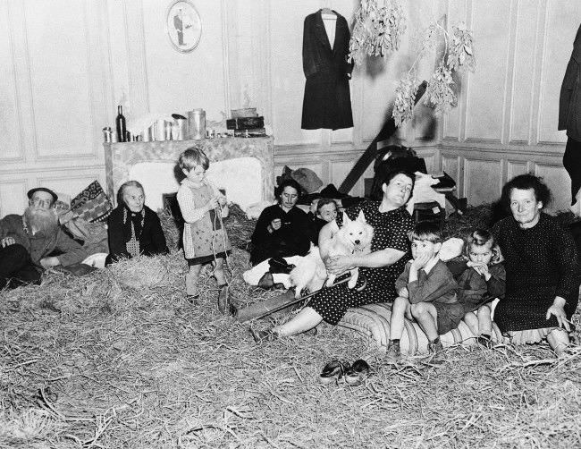 Old and young, these refugees from the French town of St. Lo, in Normandy, 1944, take up temporary quarters in a former mansion following their return to the newly liberated town. Straw has been placed on the floor to provide a little comfort in the house that are being cared for by Allied Civil affairs authorities.