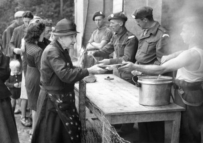 Although freedom has now been restored to parts of Normandy there remain many problems which the Allies are in process of solving. The most urgent is the housing of thousands of refugees, many of whom have fled through the German lines, to gain their freedom behind the Allied lines. Families have been split up and the task of re-uniting them is very difficult. British troops serving food to the refugees in the liberated town of Bayeux and the surrounding area in France, 1944.