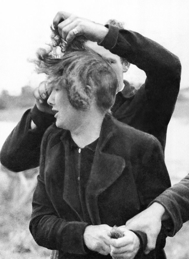 Grande Guillotte, a 23 year-old French girl collaborated with the Germans in Normandy. When her town was liberated by Allied troops, French patriots dragged her from her house and cut off all her hair. A French patriot cuts off Grande Guillotte’s hair while another holds her in France, 1944.