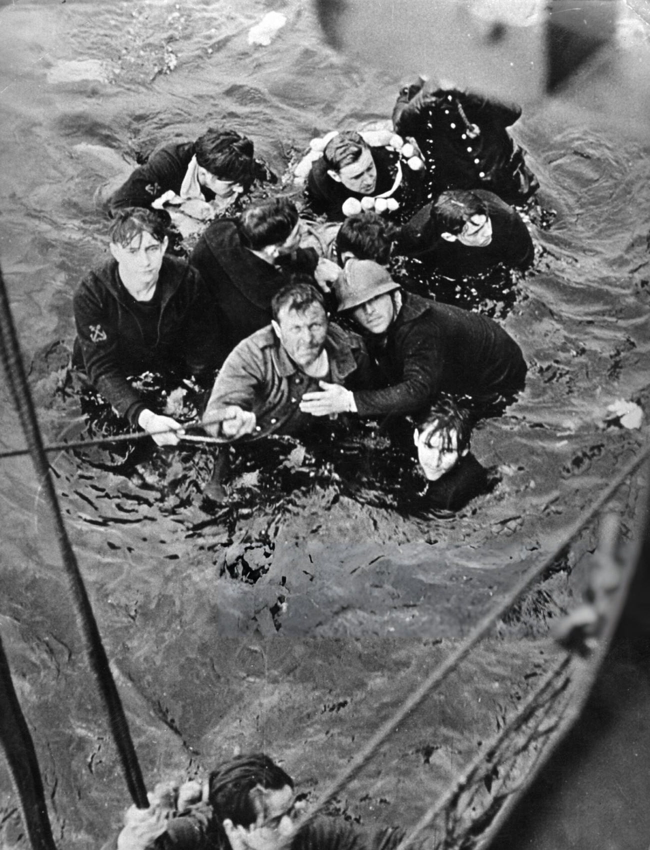 Crew members of the French destroyer Bourrasque, sunk by mine off Nieuwpoort during the Dunkirk evacuation, are hauled aboard a British vessel from their sinking life-raft, 1940.