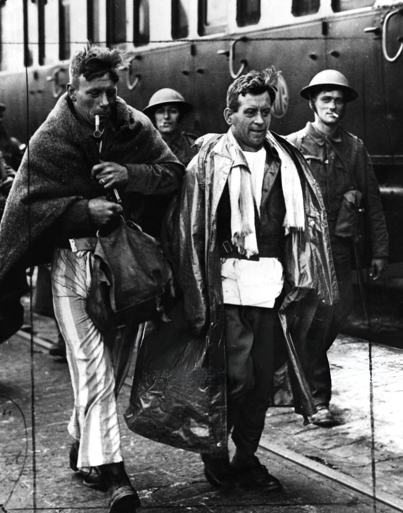 Two soldiers arrive back in England after being evacuated from Dunkirk. One of them is only wearing his pyjamas, 1940.