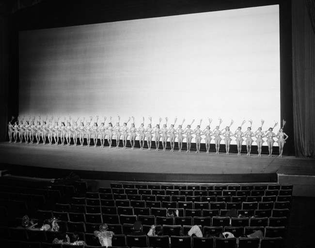 To accent the size of the giant 70-foot-wide new screen at Radio City Music Hall, the Rockettes stretch across the stage, 1954.