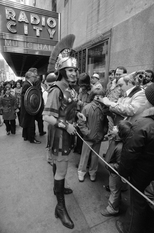 Costumed Rosemary Novellino, one of the famed Radio City Music Hall Rockettes, joins other Music Hall employees in collecting signatures on petitions to keep the historic hall open, 1978.