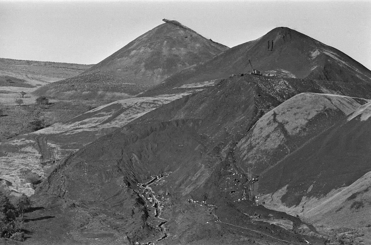 Local emergency services and miners travel high up onto the hillside, to put up sandbags along the route of the mud slide, 1966.