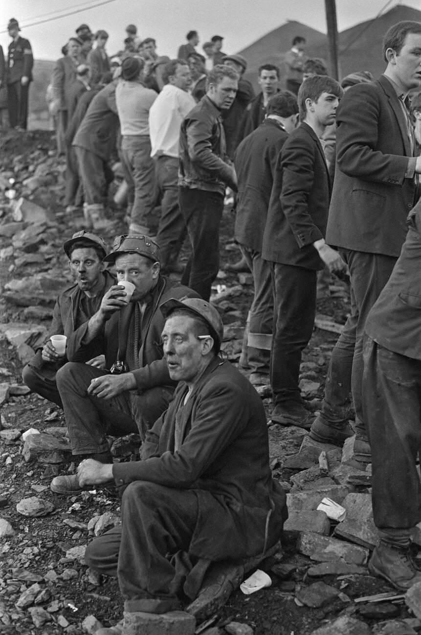 Miners take a short well earned break for a sit down, a hot drink, cigarette and to gather their thoughts as the rescue effort carries on behind them, 1966.