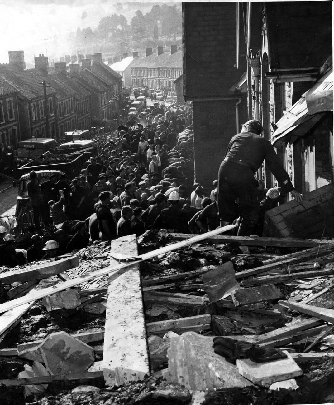 Rescue workers force their way into the crushed school building amidst the debris, 1966.