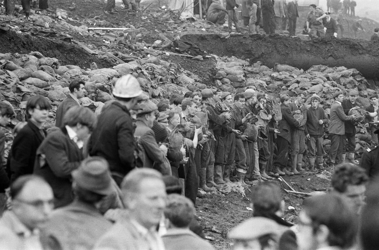 Men line up to pass sandbags filled with the hillside mud, away from the disaster zone, 1966.