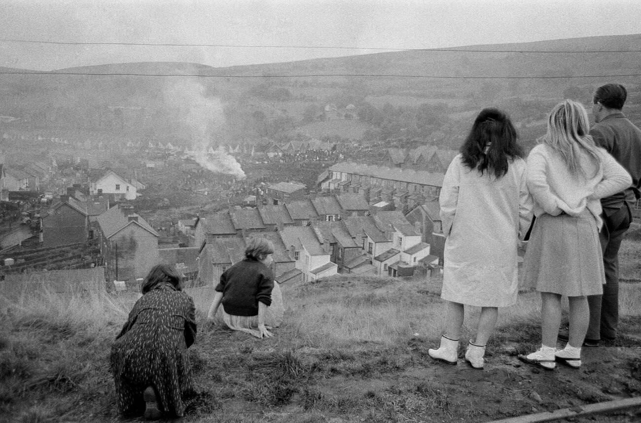 Children on the hillside overlooking Aberfan watch as a bonfire is made near to where the mud slide has come to a halt, to burn the wood and wreckage of the school and local houses, 1966.