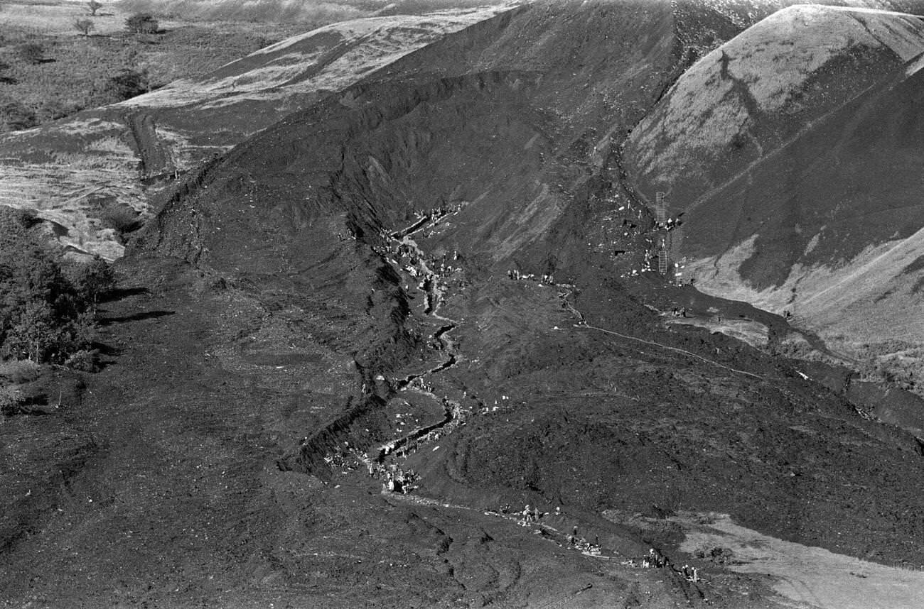 Local emergency services and miners travel high up onto the hillside, to put up sandbags along the route of the mud slide, 1966.