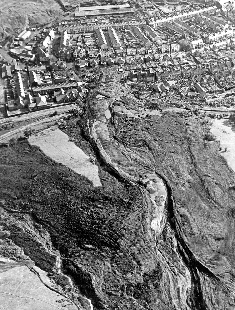 An aerial picture shows the top of the mountain and the mining spoil that has run down the hillside destroying the school and part of the town, 1966.