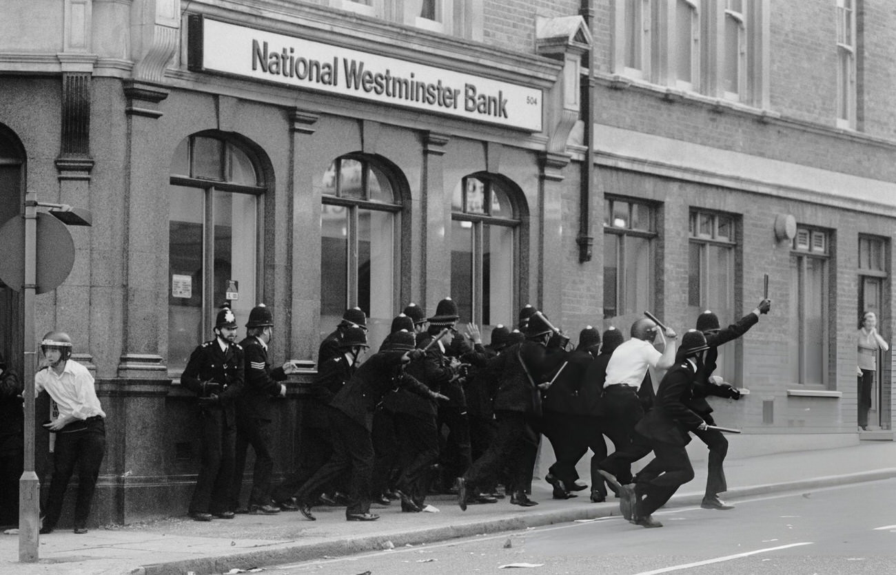 A group of policemen run with batons outside a National Westminster Bank during the Brixton Riot of April 11, 1981.