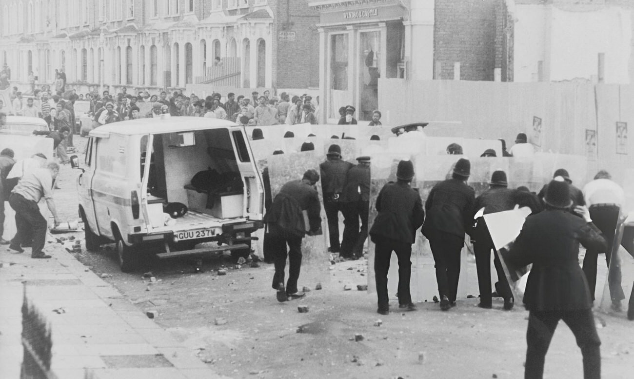 Police officers with riot shields approach a group of protesters during the Brixton Riot, London, 1981. The uprising was caused by the discontent within the Black community with the 'Sus Law' and the disproportionate use of police powers against black people.