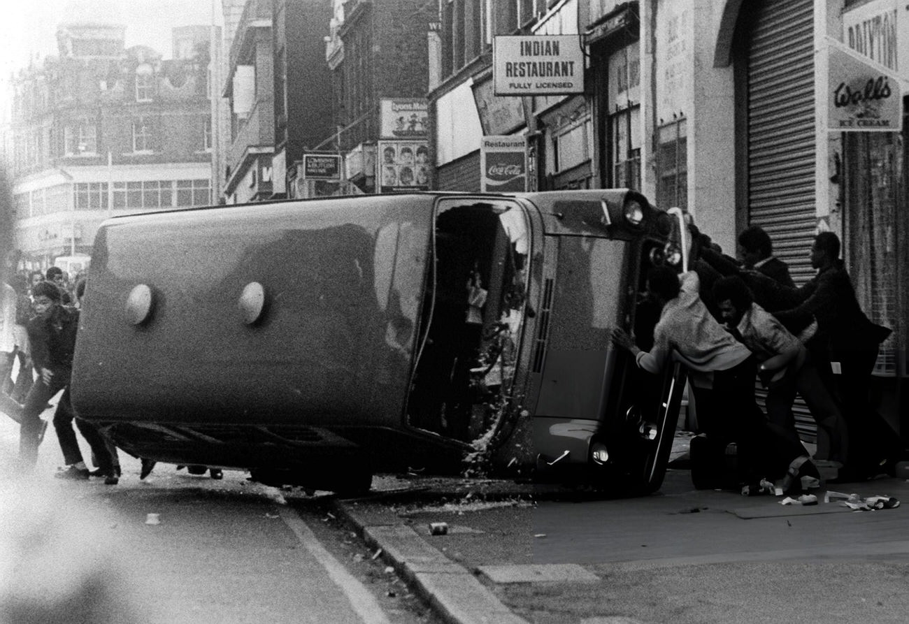 A Police vehicle is turned over at Brixton, South London, 1981.