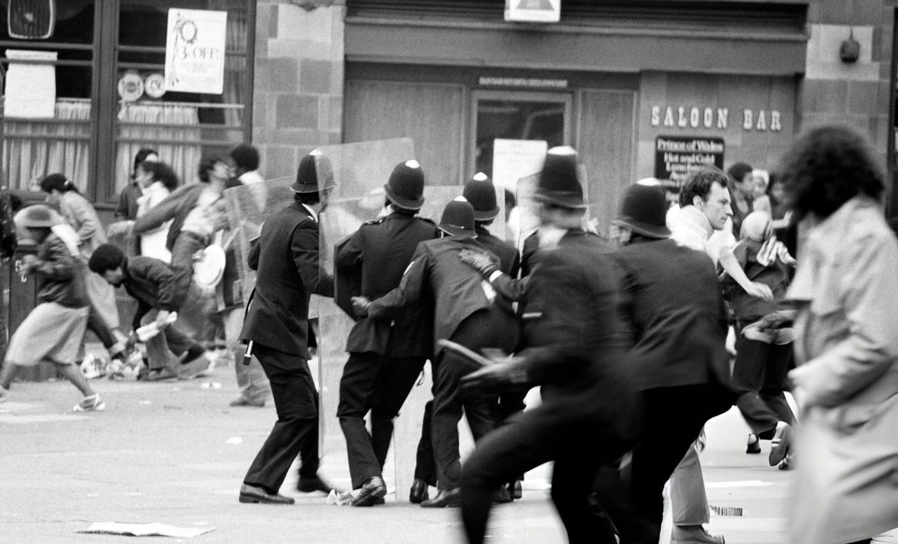 Armed with riot shields, police huddle together for protection as violence again flared near Lambeth Town Hall in Acre Lane, Brixton, south London, where between 200 and 400 black youths were on the rampage. Rioters smashed shop windows in the Brixton Road and began looting. Police squads moved in on foot and by van, 1981.