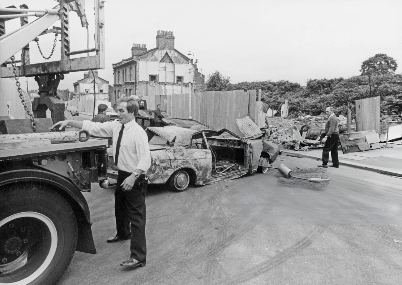 Recovery men towing away a burnt-out car after a night of violence on the streets of Brixton, London, England, 1981. Starting in April, rioting continued in Brixton and it was not until the end of July that the unrest began to subside.