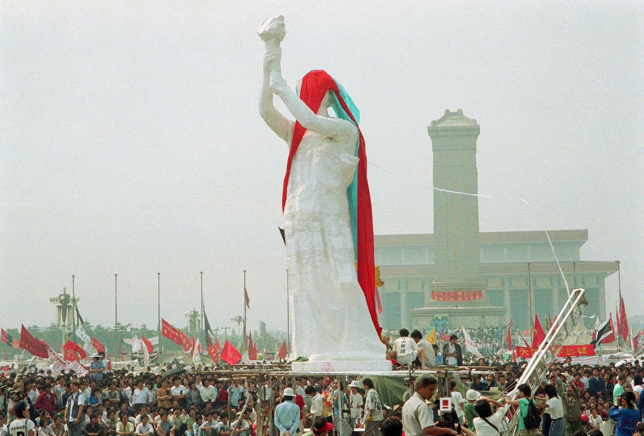 Crowds of people watch the unveiling of the "Goddess of Democracy" sculpture in Tiananmen Square. The Monument to the People's Heroes and Mao Zedong Mausoleum are visible in the background.