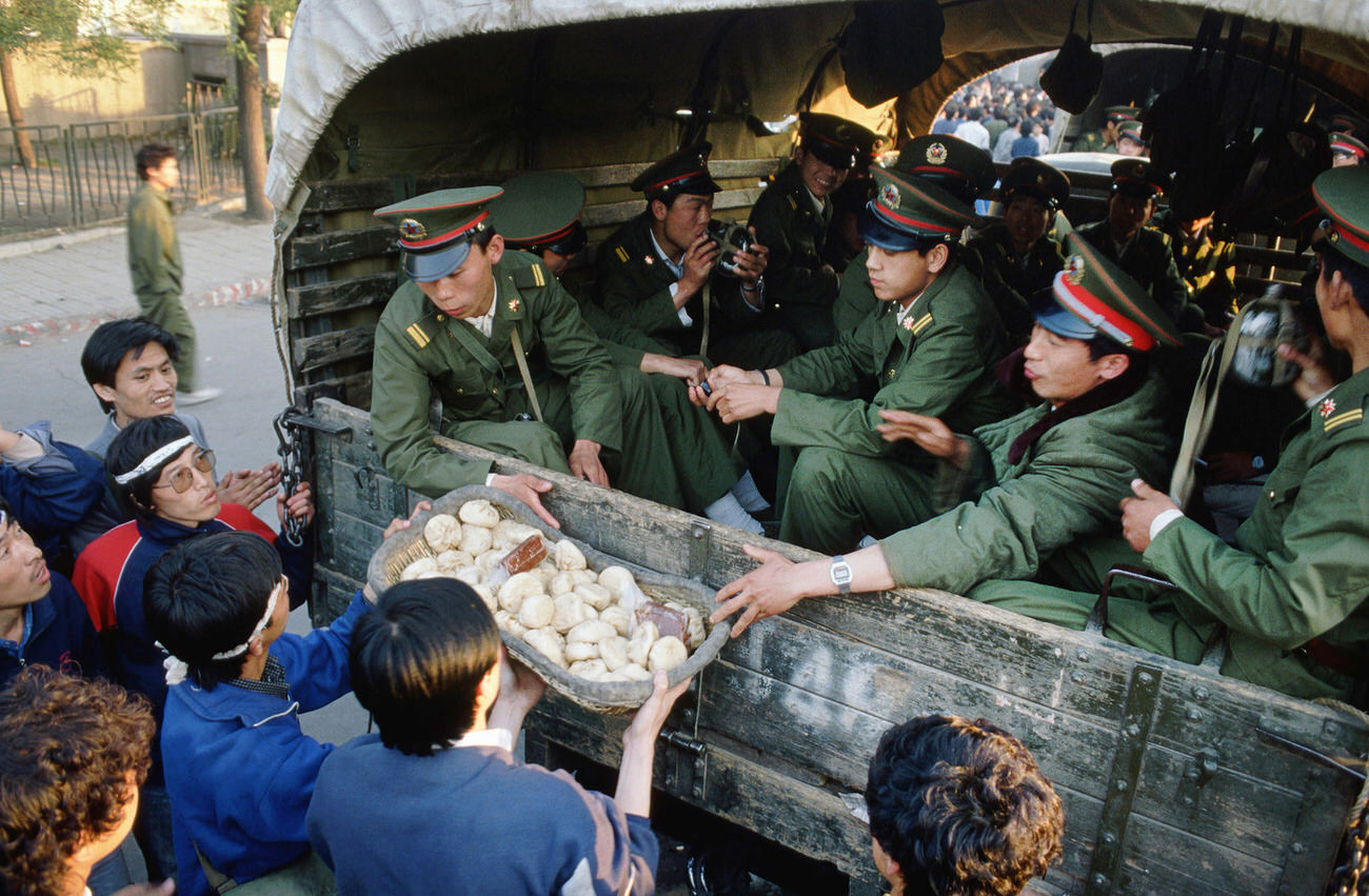 The day after the Chinese government declared martial law, students, protesters, and thousands of Beijing residents and workers in sympathy with them flooded the streets and peacefully persuaded the troops not to continue on to Tiananmen Square. They often gave the troops food.