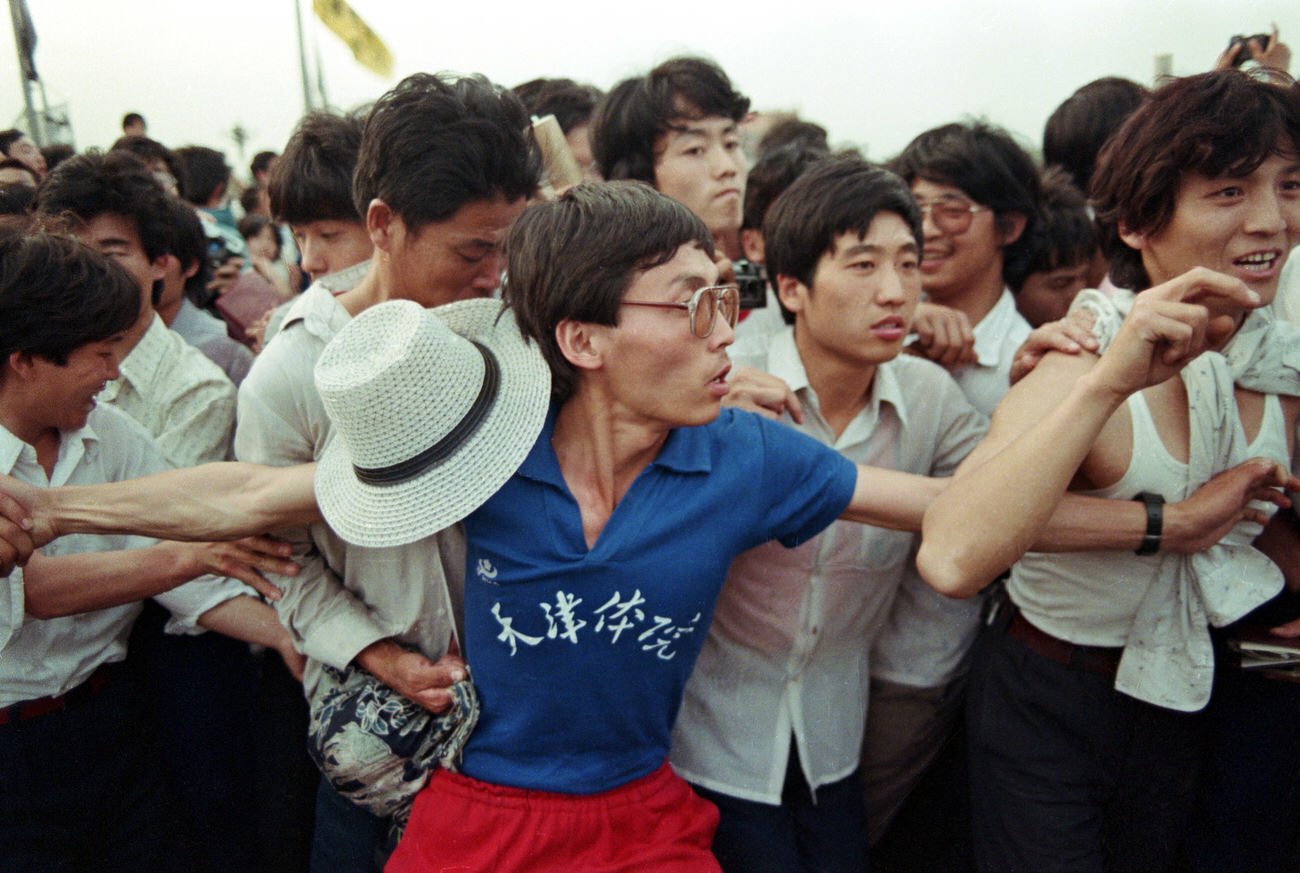 A man attempts to hold back the swelling crowd.