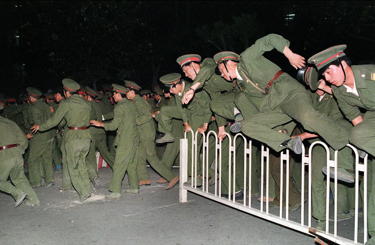 PLA soldiers leap over a barrier on June 4, 1989, during heavy clashes with people and dissident students.