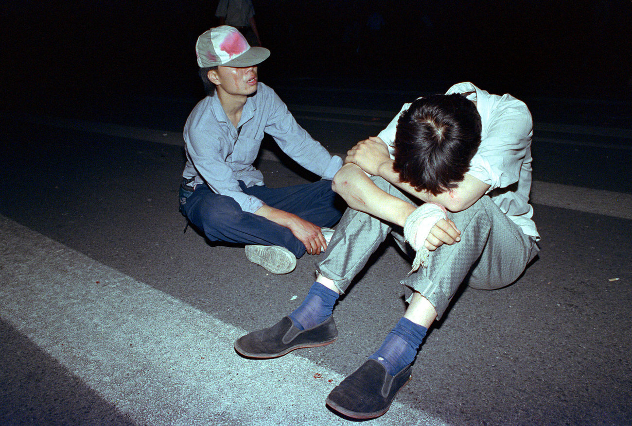 Grieving and blood-soaked students rest in Tiananmen Square.