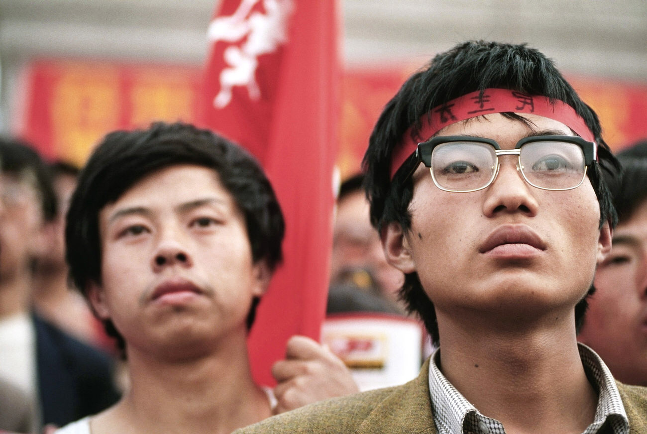 Protesters holding red banners listen to a pro-democracy movement leader speak early one morning in Tiananmen Square.