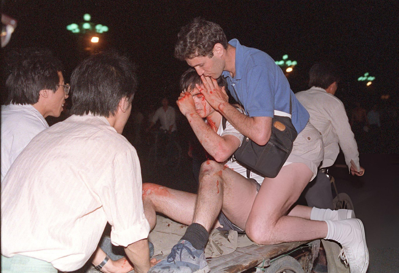 An unidentified foreign journalist is carried out from the clash site between the army and students, 1989.