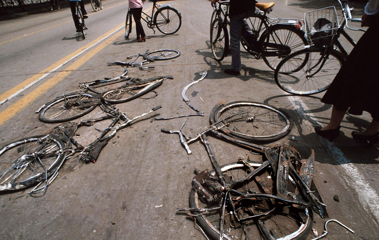 Cyclists stop to look at bicycles flattened by the Chinese army tanks, 1989.