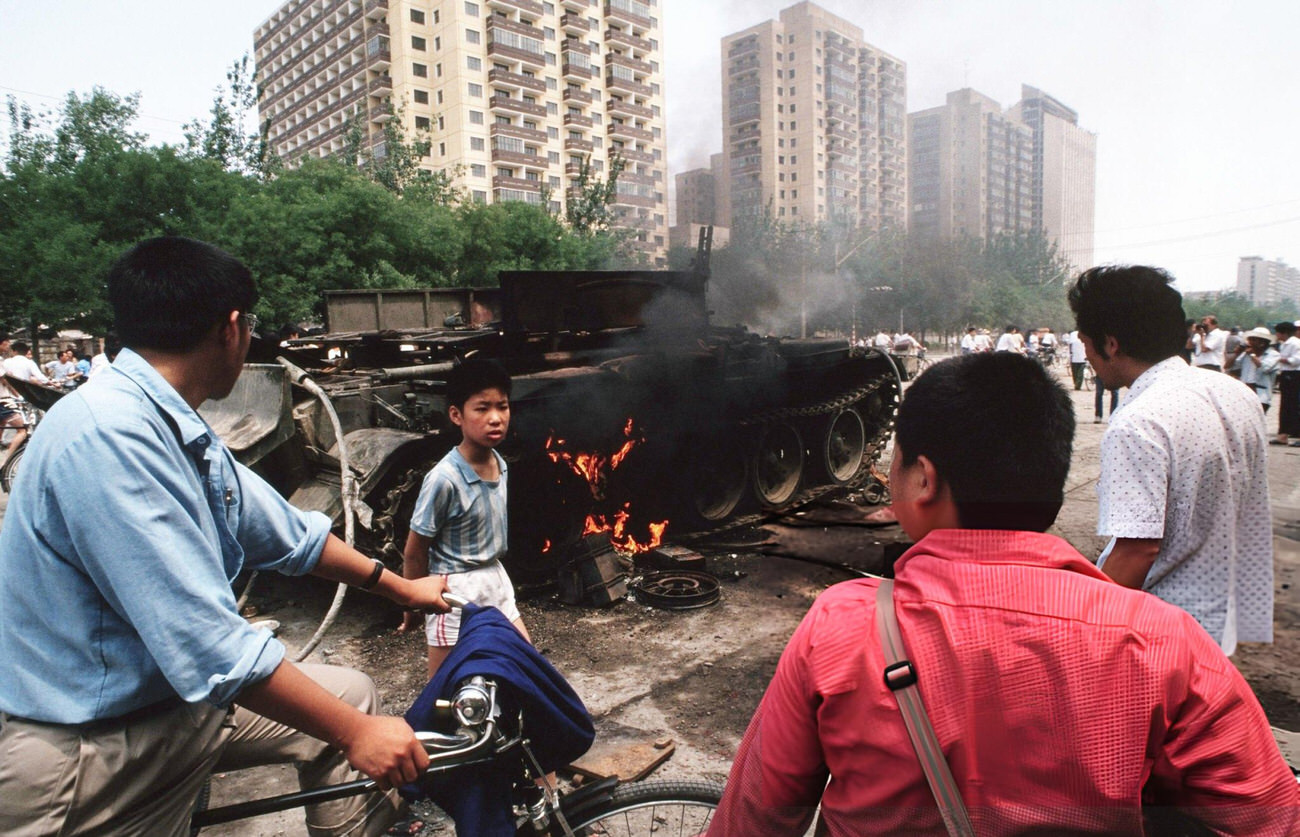 Onlookers examine Chinese Army trucks and vehicles that were damaged or destroyed, 1989.