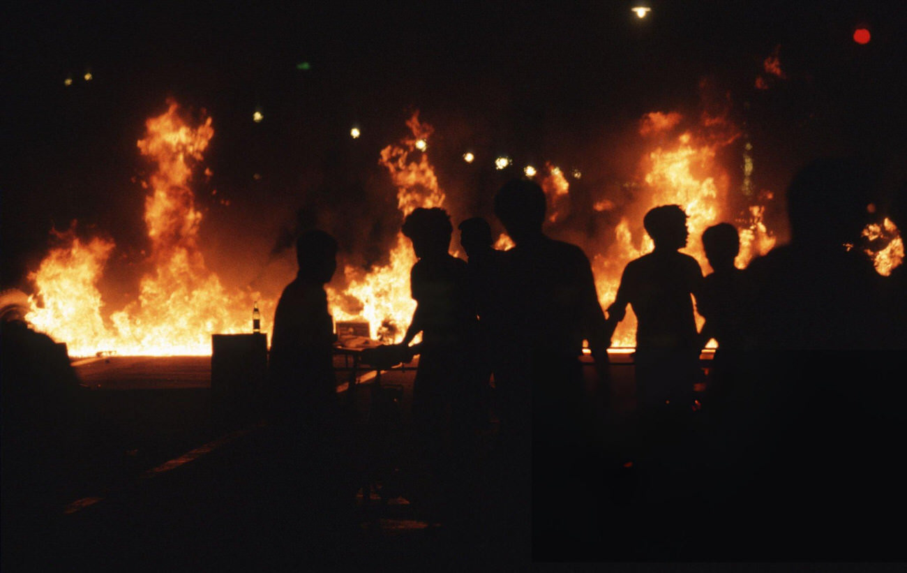 Buses and vehicles burn and pro-democracy demonstrators retreat down Chang'an Avenue, 1989.