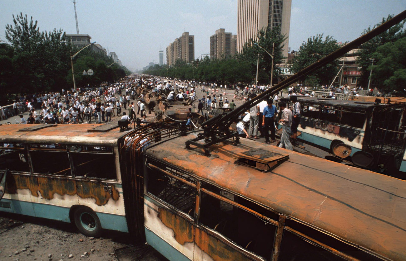 Onlookers look at buses and Chinese Army trucks and vehicles that were damaged or destroyed, 1989.