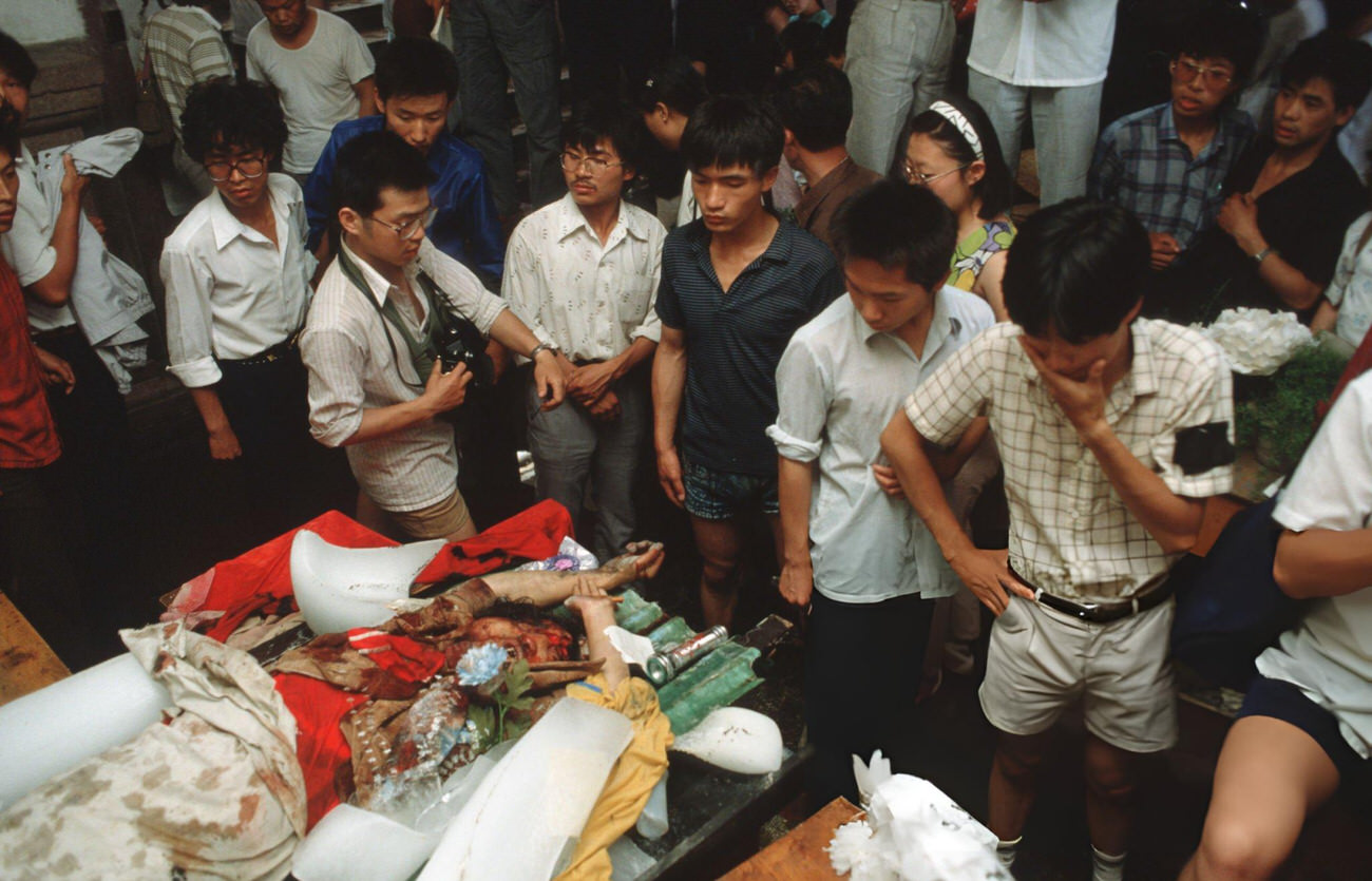 Onlookers examine the dead body of a protestor lying in a temporary morgue, 1989.