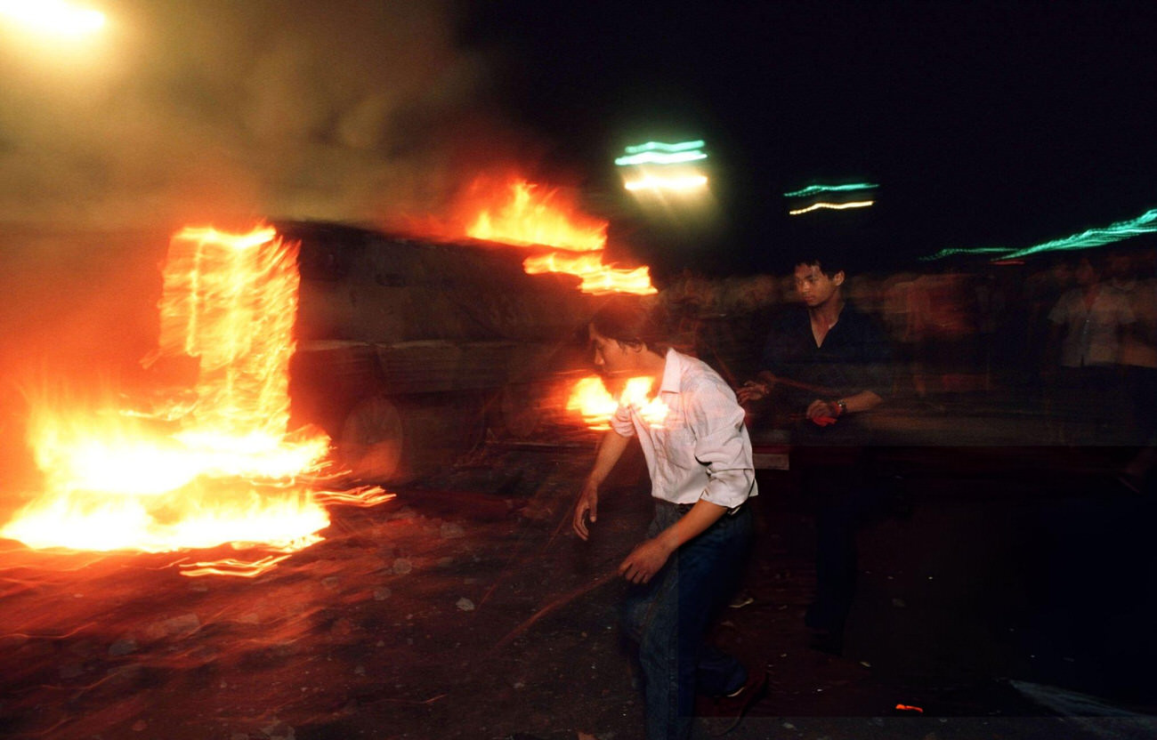 As a military vehicle burns, pro-democracy demonstrators flee down Changan Avenue, 1989.