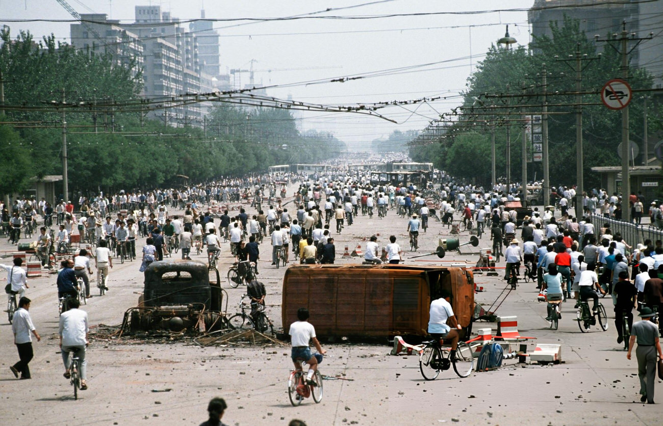 Onlookers examine Chinese Army trucks and vehicles that were damaged or destroyed, 1989.