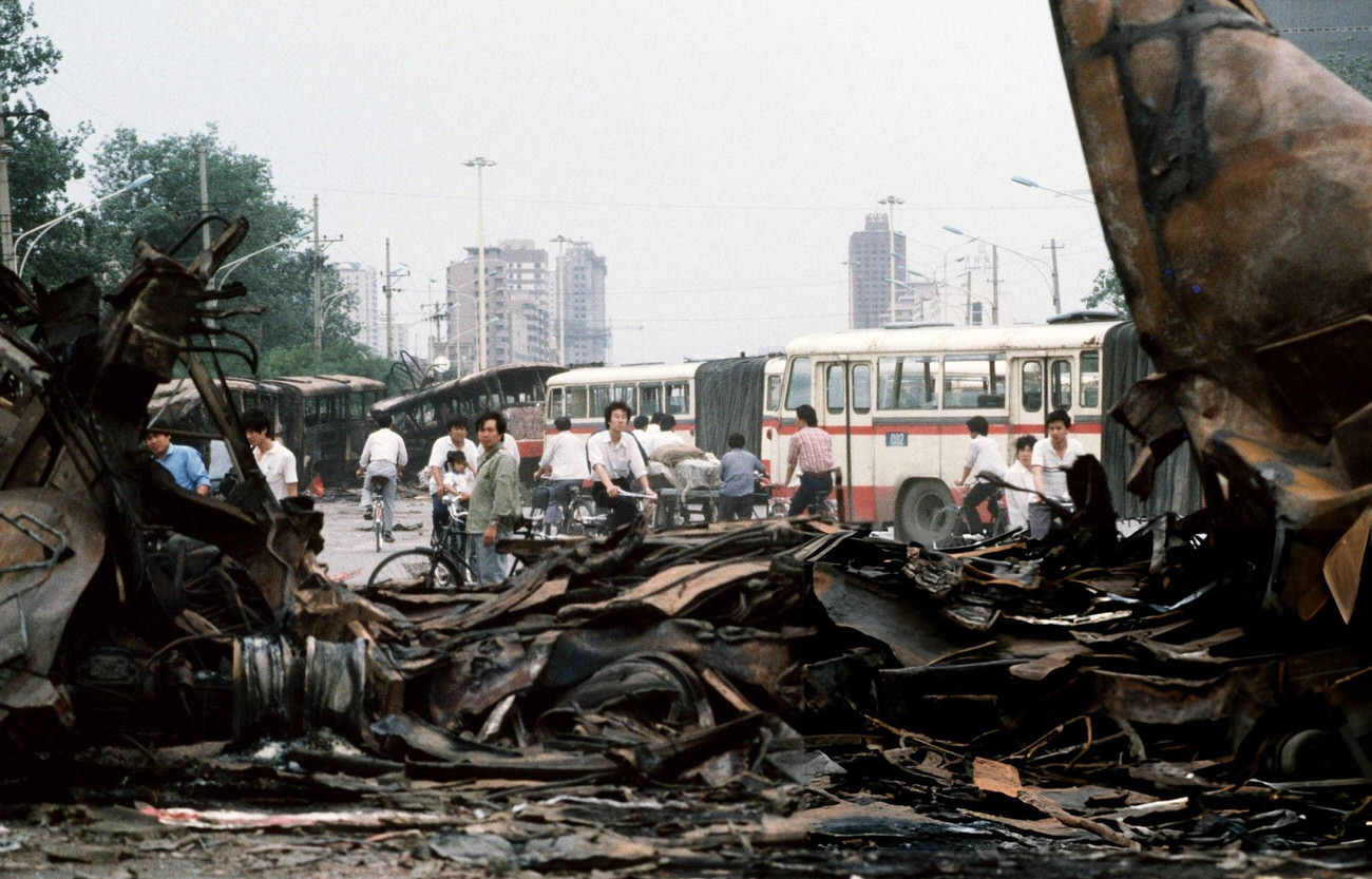 Onlookers examine destroyed buses, once barricades, that were run over by Chinese Army tanks, 1989.