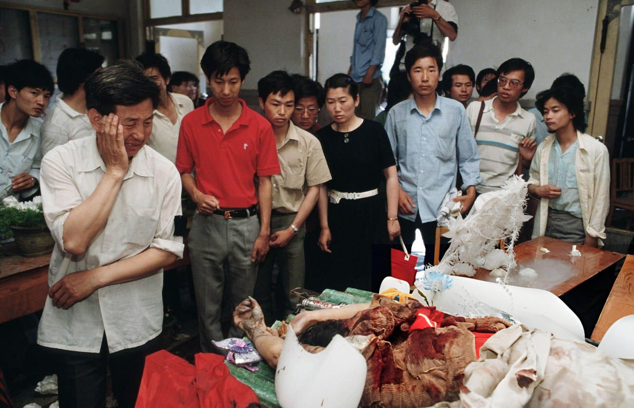 Onlookers examine the dead body of a protestor lying in a temporary morgue, 1989.