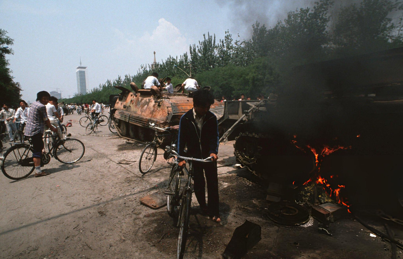 Onlookers examine Chinese Army trucks and vehicles that were damaged or destroyed, 1989.