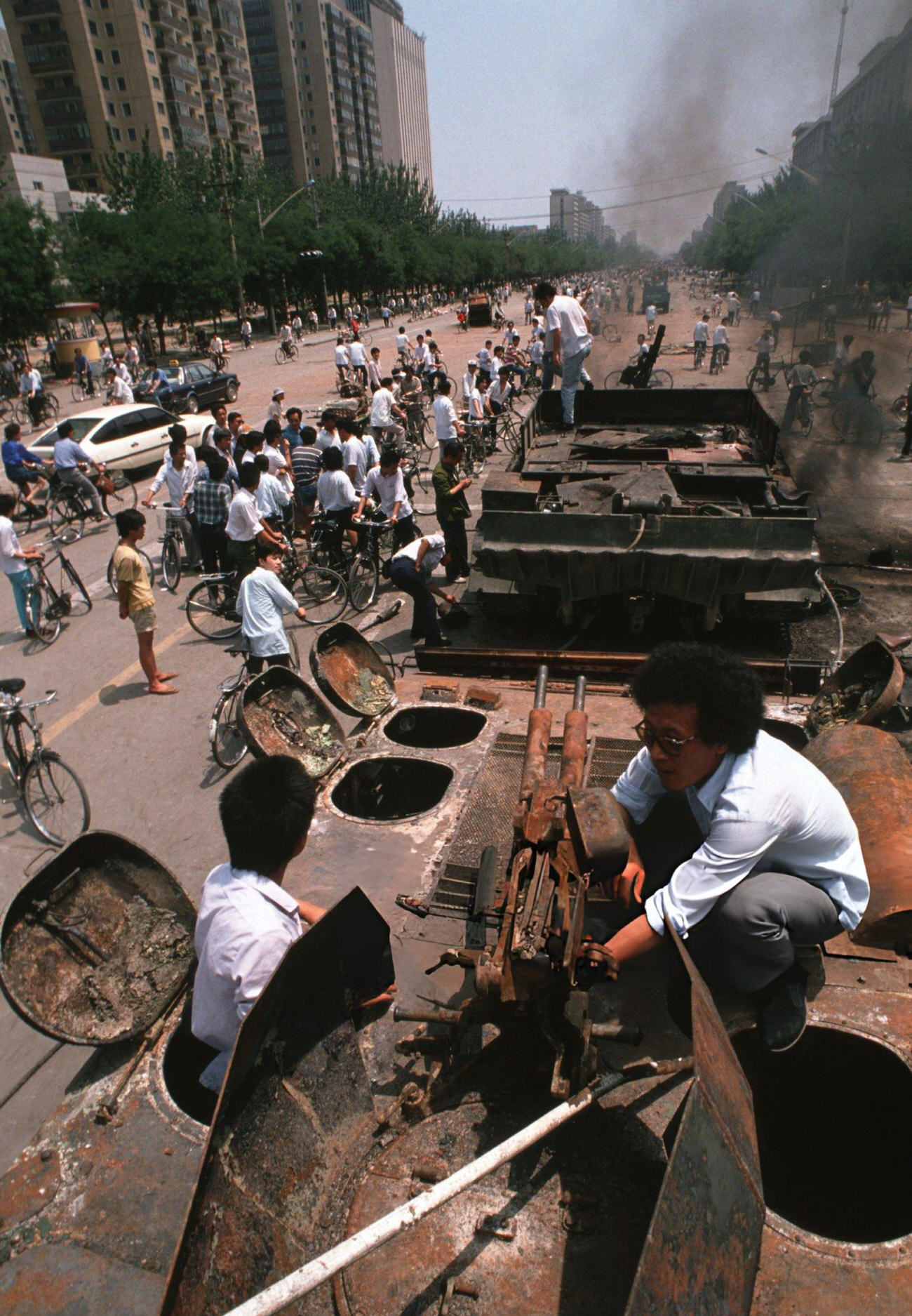 Onlookers examine Chinese Army trucks and vehicles that were damaged or destroyed, 1989.